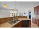 A kitchen island with stainless steel sink, wooden cabinets, and recessed lighting at 1221 Cochrane Woods Ln, Matthews, NC 28105