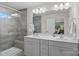 Bathroom featuring double sinks, gray cabinets, large mirror and tiled walk-in shower at 16022 Red Buckeye Ln, Huntersville, NC 28078