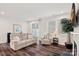 Comfortable living room features a sofa, armchair, dark hardwood floors, and natural lighting at 16022 Red Buckeye Ln, Huntersville, NC 28078