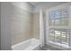 Bright bathroom featuring a tiled shower/tub, a shower curtain, and a window with shutters at 220 Ambleside Village Ln, Davidson, NC 28036