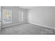 Bright, carpeted bedroom with two large windows bringing in natural light at 220 Ambleside Village Ln, Davidson, NC 28036