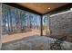 Outdoor patio with stone floor, wood ceiling, and a view of a lake surrounded by trees at 220 Ambleside Village Ln, Davidson, NC 28036