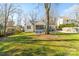 Expansive backyard features a mature tree, lush lawn, a patio with chairs, and a charming white house at 3939 Sussex Ave, Charlotte, NC 28210