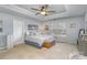 This main bedroom features a tray ceiling, a large window, neutral walls and carpet, and a ceiling fan at 4763 Brockton Nw Ct, Concord, NC 28027