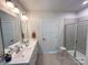 Bright bathroom featuring double sinks, large mirrors, tiled floors, and a glass-enclosed shower at 5047 Summer Surprise Ln, Charlotte, NC 28215