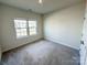 Well-lit bedroom with neutral carpet and walls, and a large window offering natural light at 5047 Summer Surprise Ln, Charlotte, NC 28215