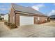 Attached brick garage with white door and landscaping at 573 Church St, Locust, NC 28097