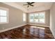 A light-filled bedroom with hardwood floors, a ceiling fan, and three bright windows at 6098 Ballard Rd, Denver, NC 28037