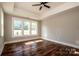 A light-filled bedroom with hardwood floors, a ceiling fan, and three bright windows at 6098 Ballard Rd, Denver, NC 28037