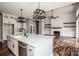 Open-concept kitchen and living area with fireplace, white cabinets, and modern lighting at 6098 Ballard Rd, Denver, NC 28037