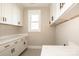 Well-lit laundry room featuring white cabinets with dark hardware, white countertops, and patterned tile floors at 6098 Ballard Rd, Denver, NC 28037