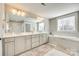 Bright bathroom with marble tiling, a soaking tub, and a large vanity with double sinks and a large mirror at 7191 Three Kings Rd, Fort Mill, SC 29715