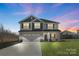 Two story home with two-car garage, a welcoming porch, and well-maintained landscaping at twilight at 821 Bethesda Rd, Statesville, NC 28677