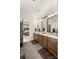 Bathroom showcasing double vanity, wood cabinets, tile floor, and doorway to bedroom at 907 Millbrook Rd, Charlotte, NC 28211