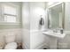 Powder room featuring a pedestal sink, wainscoting, and a window for natural light at 2201 Bluebell Way, Tega Cay, SC 29708
