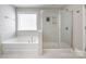 Bright bathroom featuring a soaking tub beside tiled shower with glass door and bright window at 2201 Bluebell Way, Tega Cay, SC 29708