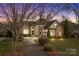 Dusk view of home featuring stone accents and mature trees, creating a tranquil and inviting setting at 2498 Smith Harbour Dr, Denver, NC 28037