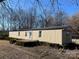 Tan mobile home with a metal roof and landscaping at 3610 Becky Ln, Monroe, NC 28112
