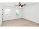 This bedroom features carpet flooring, white walls, two windows for natural light, and a ceiling fan at 204 N Yadkin Ave, Spencer, NC 28150