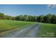 Gravel driveway leading to the property, surrounded by green field and lush trees at 4816 Zion Church Rd, Concord, NC 28025