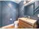 Stylish powder room with modern fixtures, wood vanity, sink, and blue accent wall at 4833 Addison Dr, Charlotte, NC 28211