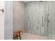 Modern shower with light blue tiling, glass door, and a comfortable wooden seat at 4833 Addison Dr, Charlotte, NC 28211