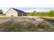 View of backyard showing the home's gray siding, dark roof, and undeveloped lot at 5177 Flay Rd, Lincolnton, NC 28021