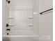 Clean, white bathroom with a shower-tub combo, built-in shelving and matte black hardware at 5177 Flay Rd, Lincolnton, NC 28021