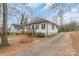 One-story home with white siding, black shutters, a long driveway and mature trees at 65 Franklin St, Wadesboro, NC 28170