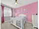 Bright bedroom features pink walls, white furniture, and natural light from the large window at 10120 Garman Hill Dr, Charlotte, NC 28214