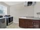 Well-equipped laundry room with modern washer, dryer, sink, storage cabinets and wire rack at 10120 Garman Hill Dr, Charlotte, NC 28214