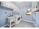 Bright laundry room with a utility sink, washer, dryer, cabinets, and a window for natural light at 1019 Palmyra Dr, Tega Cay, SC 29708