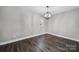 Neutral living room featuring sleek hardwood floors, modern chandelier, and a window for natural light at 1019 Palmyra Dr, Tega Cay, SC 29708