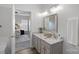 Bright bathroom with granite counters, grey cabinetry and an open doorway to the primary bedroom at 141 N Arcadian Way, Mooresville, NC 28117