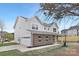 Side exterior view features a two-car garage, modern siding, and manicured lawn on a sunny day at 14309 King Eider Dr, Charlotte, NC 28273