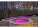 An in-ground pool and spa combination is illuminated pink at dusk at 162 Wild Harbor Rd, Mooresville, NC 28117