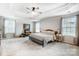 Spacious bedroom with a tray ceiling, neutral color scheme, and large windows for natural light at 2727 Cypress Oak Ln, Gastonia, NC 28056