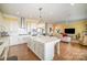 Open concept kitchen with white cabinets, island, and views into living room at 328 Sensibility Cir, Fort Mill, SC 29708