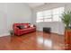 Bright living room featuring hardwood floors, large windows, and a comfortable red leather sofa at 3867 Azalea Trl, Denver, NC 28037