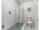 Updated bathroom features a glass shower with blue tile, a modern toilet, and mosaic tile flooring at 3995 Burton Ln, Denver, NC 28037