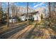 A charming house with a screened-in porch and backyard shed is surrounded by trees and greenery on a sunny day at 781 Woodlawn Ave, Mount Holly, NC 28120