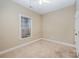 This bedroom features neutral walls and carpet, a ceiling fan, and a window allowing natural light into the space at 781 Woodlawn Ave, Mount Holly, NC 28120