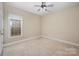 This bedroom features neutral walls and carpet, a ceiling fan, and a window allowing natural light into the space at 781 Woodlawn Ave, Mount Holly, NC 28120