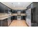 Well-lit kitchen with dark cabinets, stainless steel appliances, and tile flooring at 781 Woodlawn Ave, Mount Holly, NC 28120