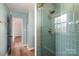 Close-up of a shower with green tile, glass door, and gold fixtures at 8025 Cliffside Dr, Charlotte, NC 28270