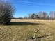 Expansive backyard featuring a grass field with the background of distant trees under the clear blue sky at 897 Mocksville Hwy, Statesville, NC 28625