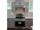 This kitchen features a stainless steel range with white subway tile backsplash and gray cabinets at 105 N Inman Ave, Bessemer City, NC 28016