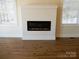 Living room showcases a modern electric fireplace, and light wood floors, complemented by large windows at 1120 Cedar St, Mount Holly, NC 28120