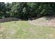 Backyard featuring grassy lawn, trees, wooded backdrop, and a wooden fence at 1128 Tangle Ridge Se Dr, Concord, NC 28025