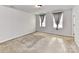 Carpeted bedroom with a neutral paint, two windows with curtains, and a door at 1128 Tangle Ridge Se Dr, Concord, NC 28025
